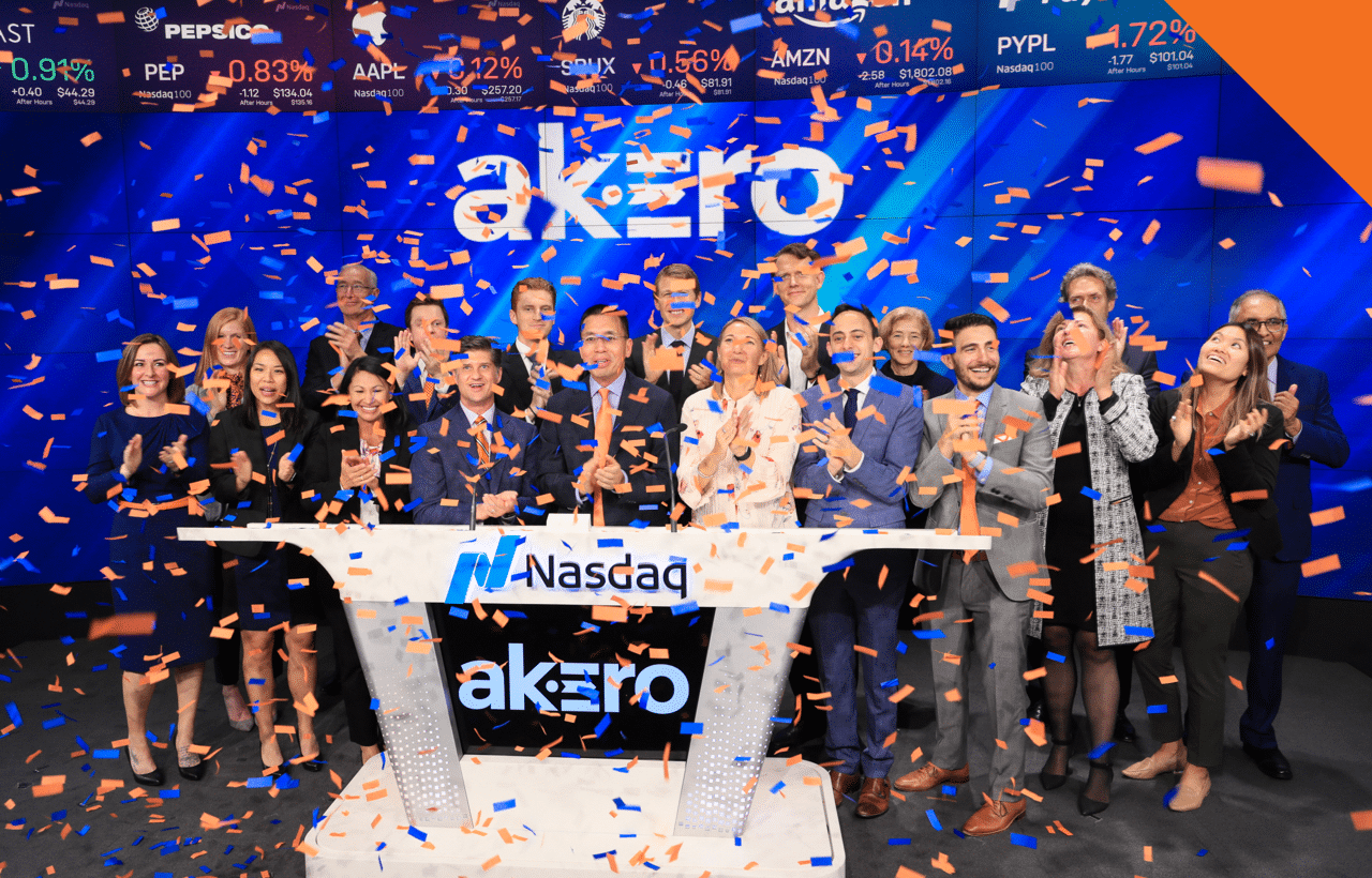 Akero employees celebrate behind a podium at NASDAQ headquarters as confetti falls