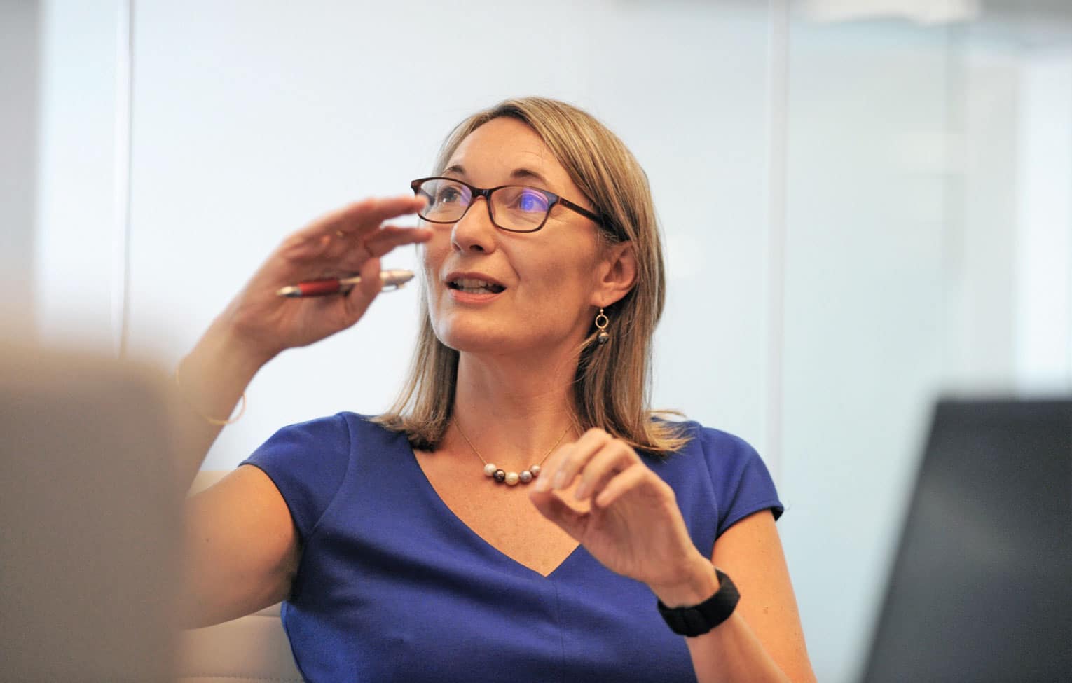 A close-up of an Akero executive holding a pen and speaking with someone out of frame
