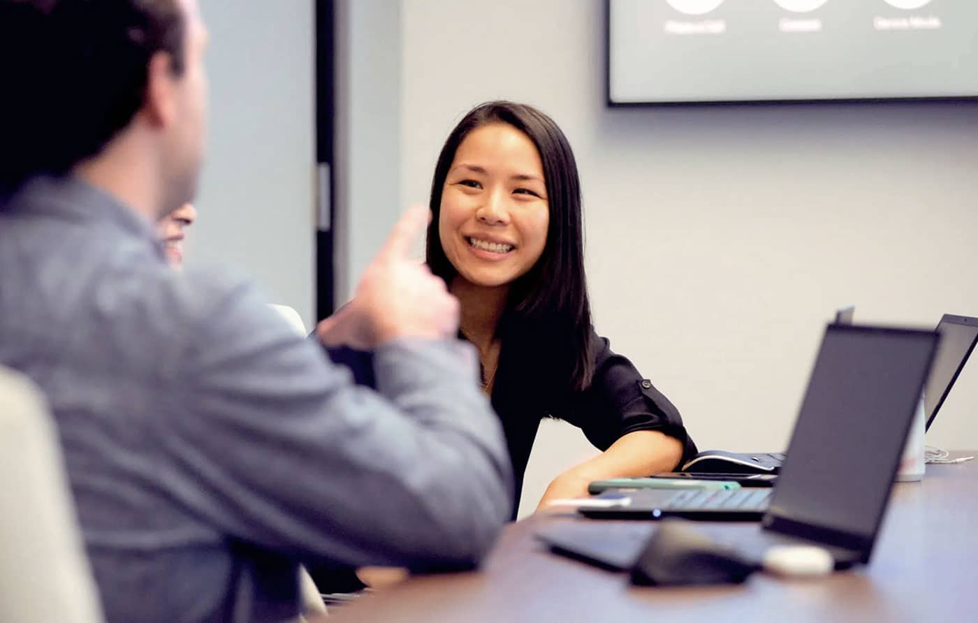 Akero employee smiling and talking to a man in a conference room