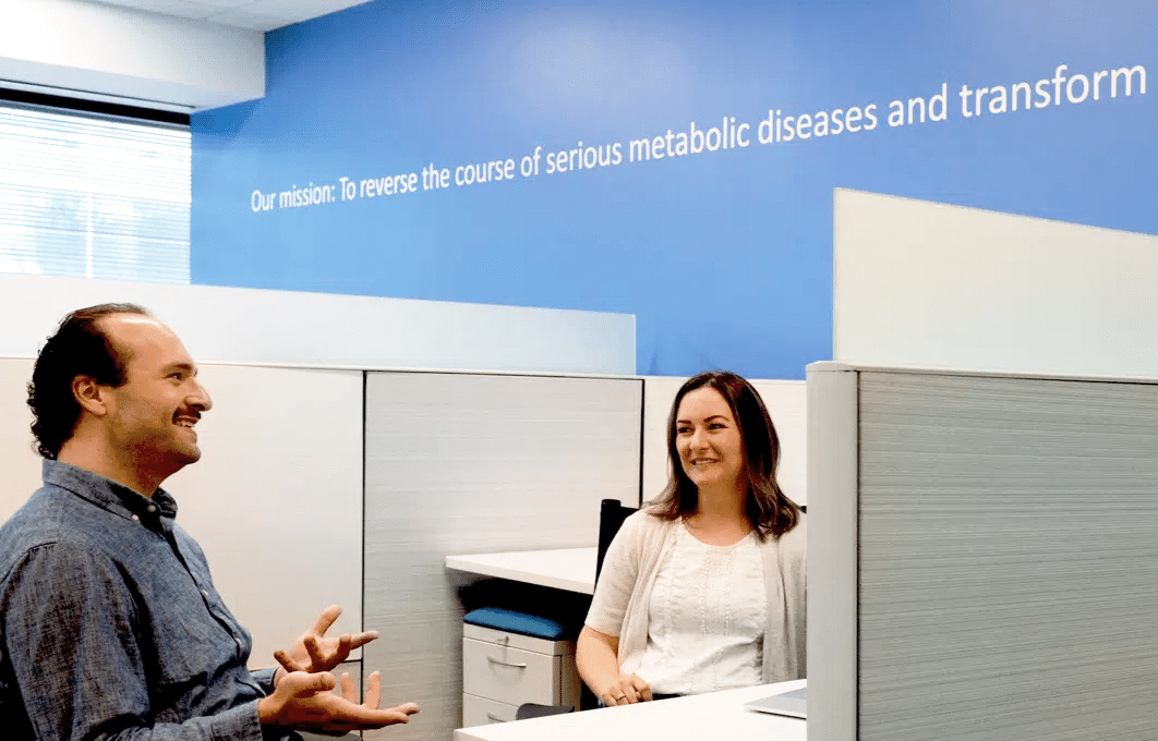 Two Akero employees conversing in an office cubicle