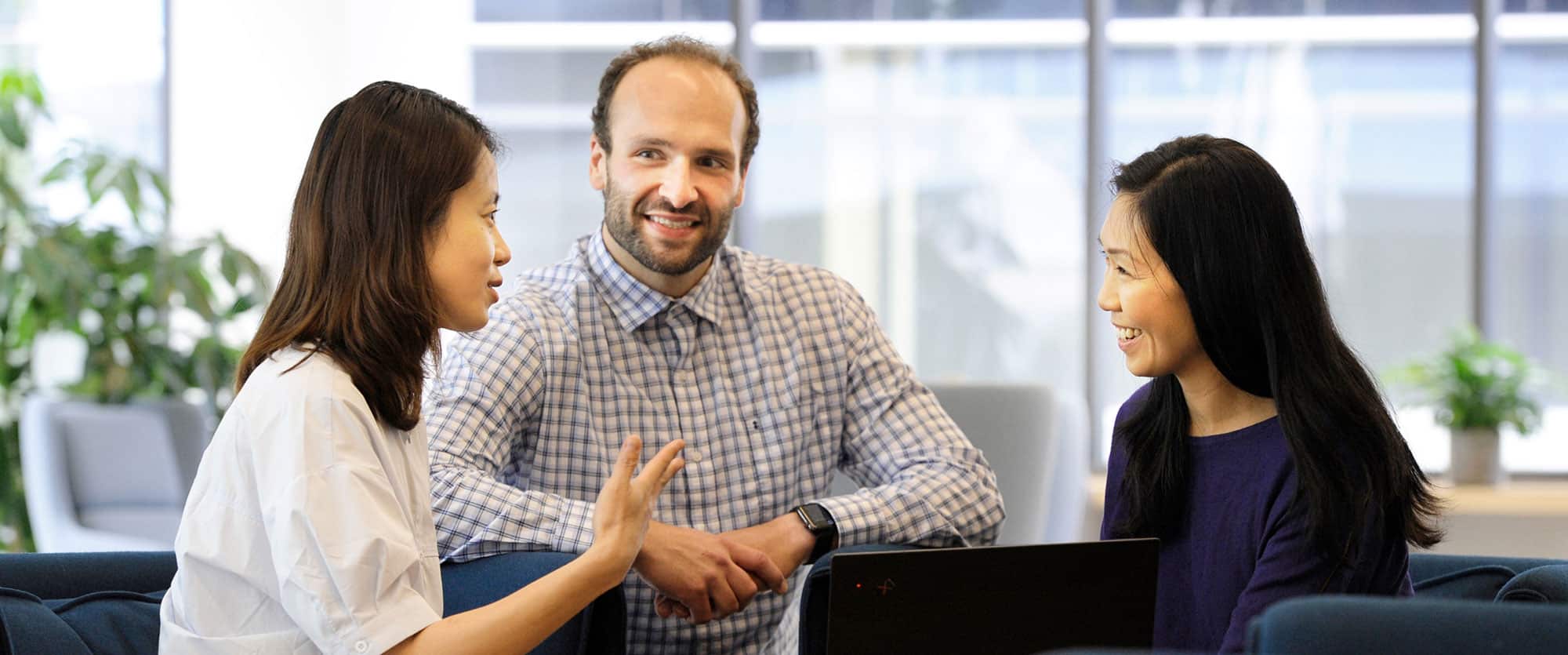 3 Akero employees smiling and conversing in a communal space