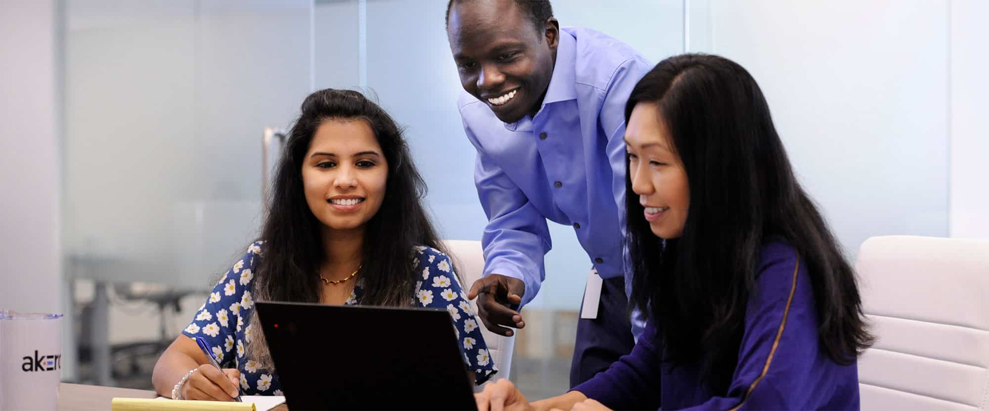Three Akero employees talking and looking at a laptop